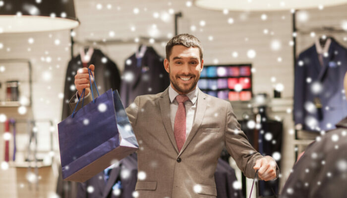 sale, fashion, retail, business style and people concept - happy man with shopping bags at clothing store over snow