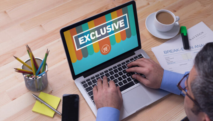 Man working on laptop with EXCLUSIVE on a screen